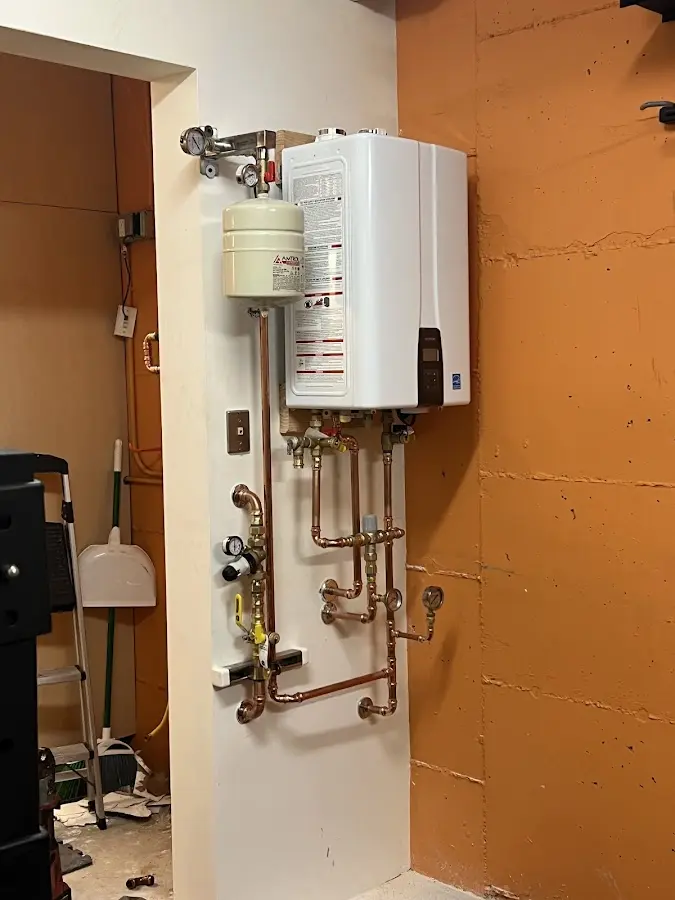 Plumbing technician inspecting water heater connections in Caribou